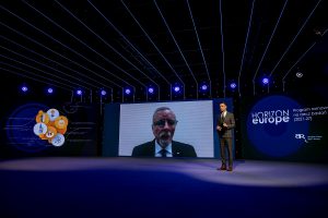 Na zdjęciu prowadzący konferencję i ekran z dyrektorem NCBR