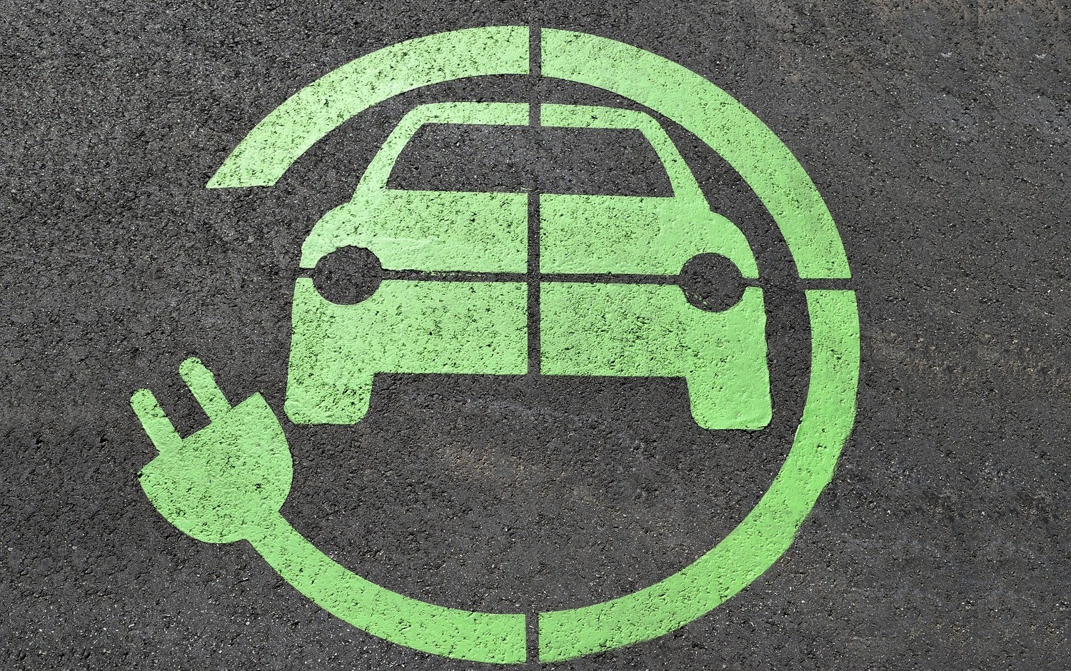 Na zdjęciu rysunek na jezdni przedstawiający zielone auto ładowane elektrycznie