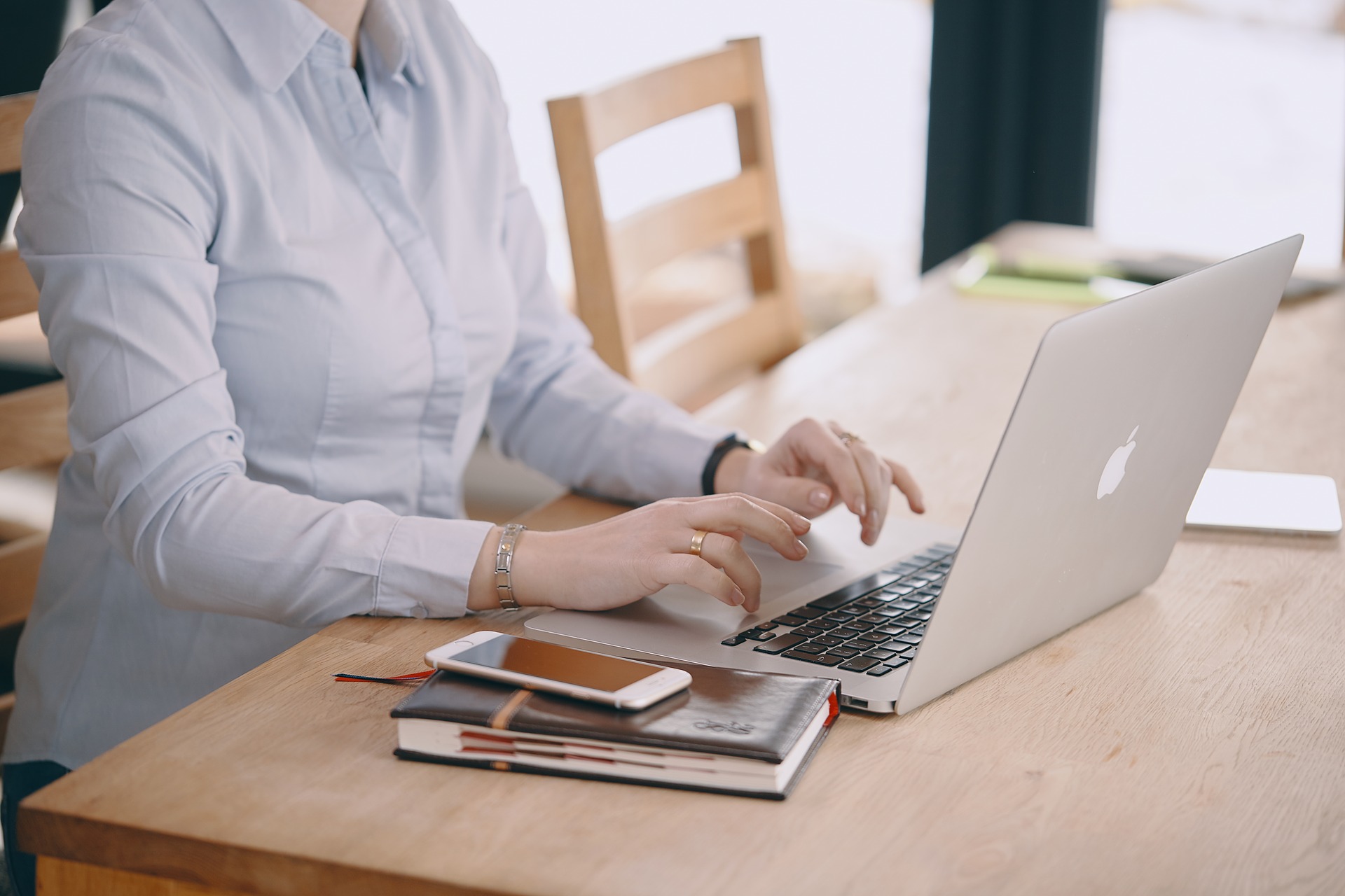 Osoba siedząca przy biurku i pisząca na laptopie